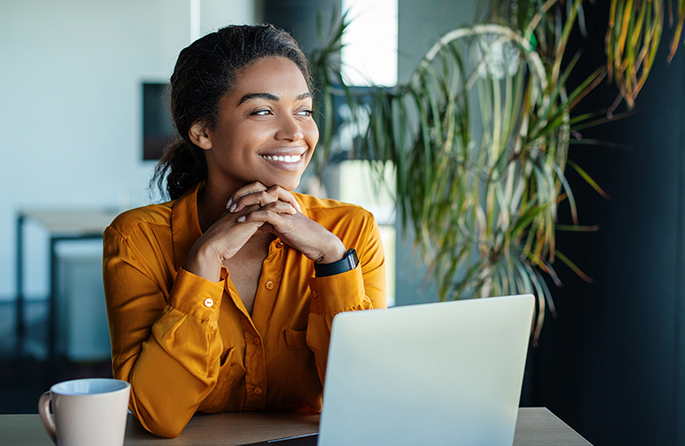 Smiling employee working on a laptop, looking to the side