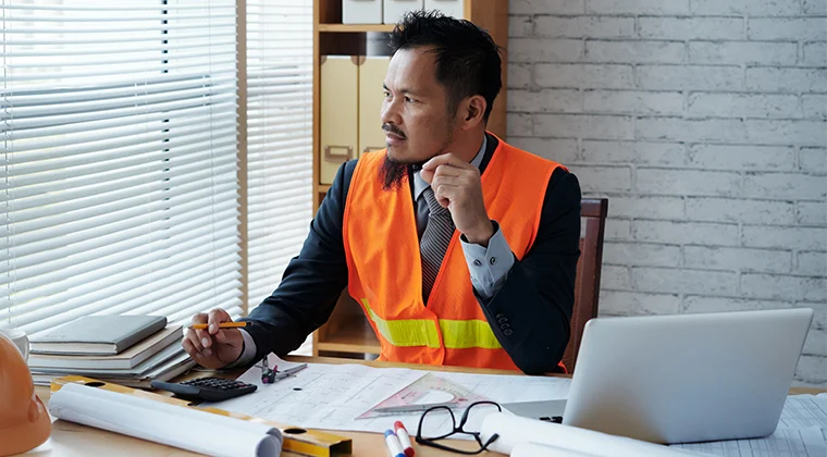 man at desk in orange safety vest