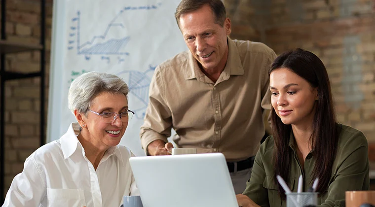 Three people looking at a laptop